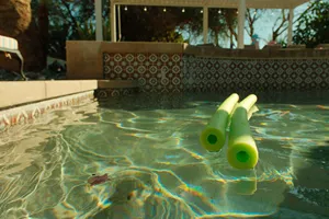Swimming Pool With Green Water And Pool Noodles In It.